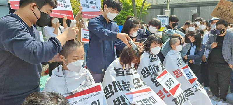 South Korean students cut hair in front of the Japanese Embassy in South Korea to protest Japan's decision to pollute water into the sea